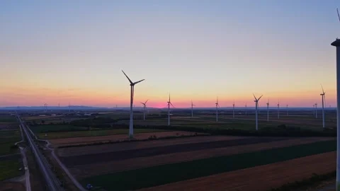 Wind turbines stand in fields at sunset in the countryside Stock Footage 342609967