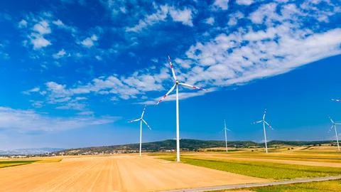 Wind turbines stand in fields under a blue sky with some clouds. Wind turbi.. Stock Photos