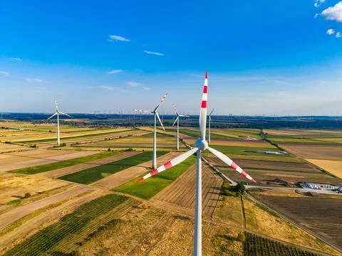 Wind turbines stand in fields under a clear blue sky in Germany during daytim Stock Photos