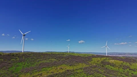 Wind turbines stand on a hilltop under a blue sky with clouds Stock Footage 338275482