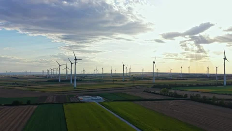 Wind turbines stand in a large field under a changing sky with clouds and Stock Footage 344153367