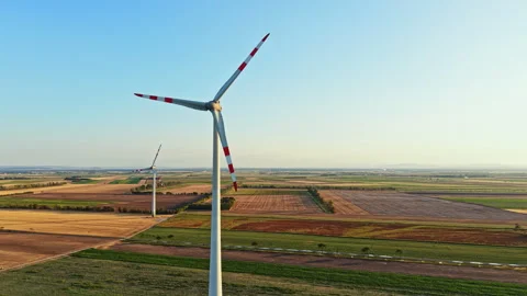 Wind turbines stand in an open field near farmland during the day with clear Stock Footage 344263456