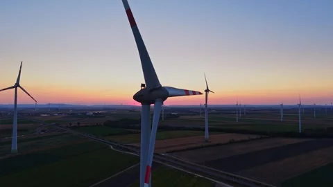Wind turbines stand in open fields at sunset with a clear sky Stock Footage 342609810