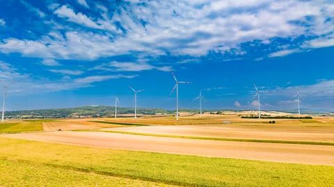 Wind turbines stand in open fields under a blue sky with clouds. Wind turbi.. Stock Photos