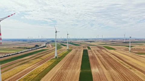 Wind turbines stand tall across green and brown fields in a wind farm on a sunny Stock Footage 342783451