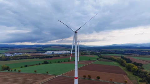 Wind turbines stand tall against a backdrop of rolling hills and dramatic clouds Stock Footage 331400985