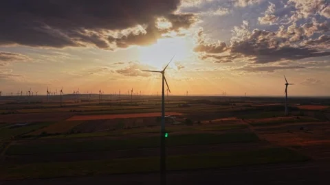 Wind turbines stand tall during sunset in an open field Vídeo Stock 343122677