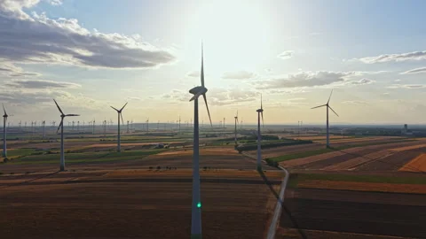 Wind turbines stand tall in a field during sunset, generating renewable energy Stock Footage 344164097