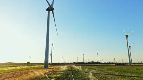 Wind turbines stand tall in a field where crops grow, showing clean energy and Stock Footage 344266818