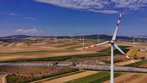Wind turbines stand tall in fields near a highway on a sunny day Stock-Footage 342605383