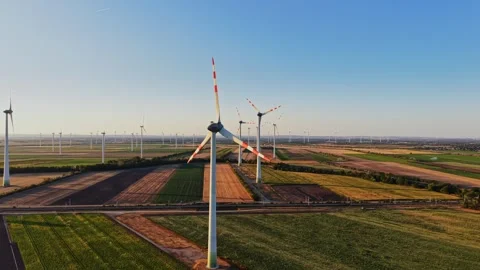 Wind turbines stand tall in open fields during clear sunny weather Video stock 342609240