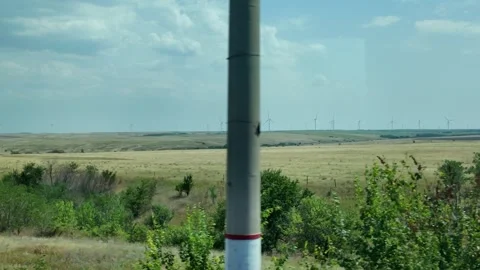 Wind turbines stand tall in an open field under a clear sky during daytime Stock Footage 344737187