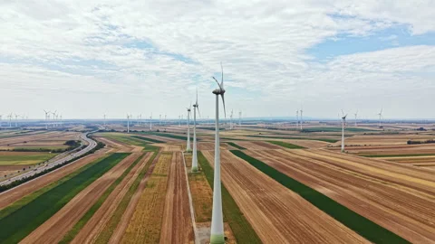 Wind turbines stand tall over flat fields in a large wind farm during a cloudy Stock Footage 342785415