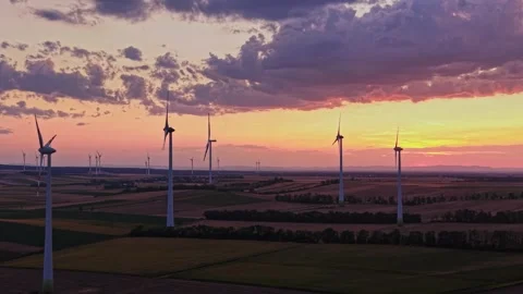 Wind turbines stand tall at sunset in a farming landscape Vidéo 343123595