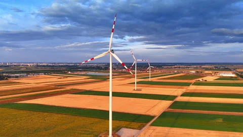 Wind turbines standing in agricultural fields under sunset sky. Aerial view of Stock Footage 339015019