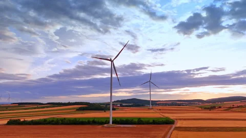 Wind turbines standing in cultivated fields near distant hills. Panoramic view Stock Footage 339014897