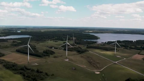 Wind turbines in summer day at fields and lake Video stock 245653728