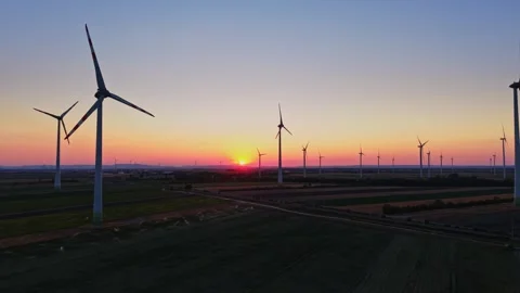 Wind turbines at sunset in an open field on a clear evening Stock Footage 342609649