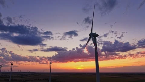 Wind turbines at sunset in an open field Stockbeeldmateriaal 343123029