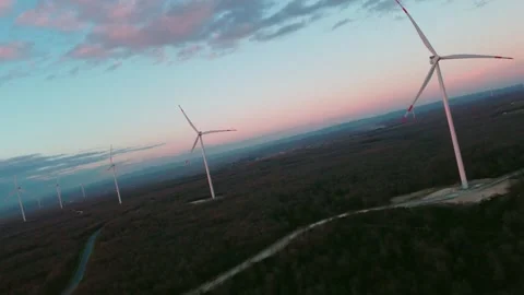 Wind Turbines at Sunset Over a Forest Landscape Stock Footage 282930340