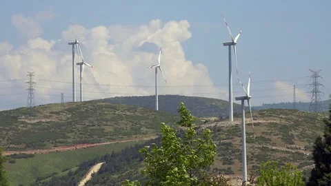 Wind turbines turn beside utility infrastructure - Fixed Camera and Power Plant Stock Footage 339644339