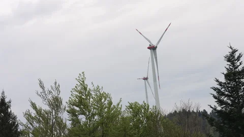 Wind Turbines Turning in a Cloudy Landscape Above a Green Forest 動画素材 338349552