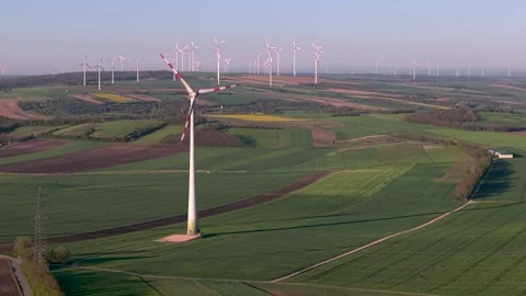 Wind turbines turning in green fields on sunny day motion footage. Stock Footage 337714404