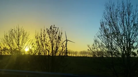 Wind turbines visible while driving on the road at sunset Stock-Footage 258277923