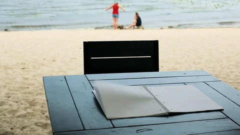 Wind turns the pages of a blank notepad lying on the table. Video stock 91360647