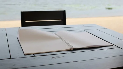 Wind turns the pages of a blank notepad lying on the table. Stock Footage 91496493