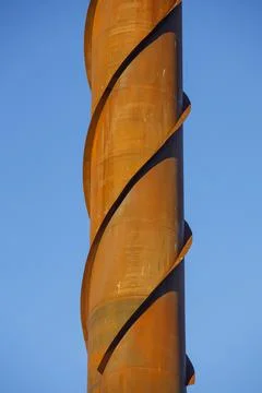 Wind vortex shedding spiral damper structure on rusty steel chimney Stock Photos