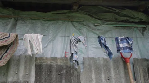 Wind waves coloured clothes hanging on rope under grey roof Stock Footage 135960423