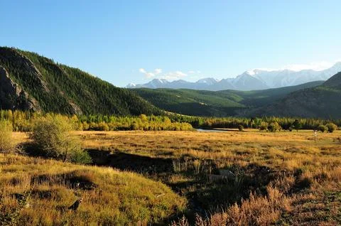 The winding bed of a dry river flows through a picturesque autumn valley at.. Stock Photos