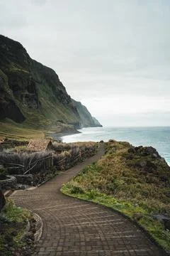 Winding cobblestone path along a rugged coast with cliffs, ocean, and cloud.. Stock-Fotos