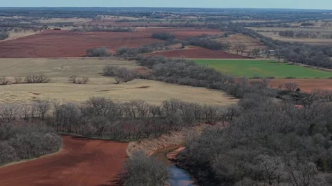 Winding Creek Through Patchwork Farmland With Red Soil Fields Aerial Oklahoma Stock Footage 329192655