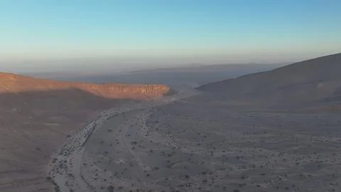 Winding Dry Riverbed Through Desert Valley at Dawn Stock Photos