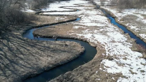 Winding flowing river through a snowy field in the winter Stock Footage 237720682