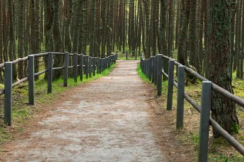 A winding footpath bordered by a rustic wooden fence invites visitors to stro Stock Photos
