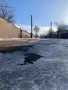 A winding, icy path stretches down a quiet street, surrounded by bare trees and Stock Photos