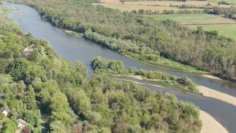 The winding Loire River bordered by dense green forests, rural farmland, and Stock Footage 346671967