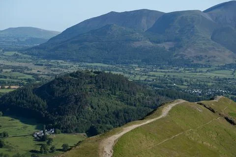 Winding Mountain Path Overlooking a Verdant Valley and Distant Peaks Stock-Fotos