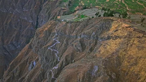 Winding mountain path toward terraced fields and distant village Stock Footage 341328278
