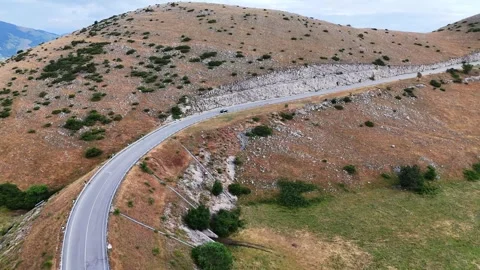 Winding Mountain Road Curves Through Scenic Landscape Under Clear Blue Sky 스톡 동영상 281289295