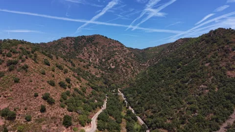 Winding mountain road cuts through a rugged valley with green shrubland slopes Vídeos de archivo 345103808