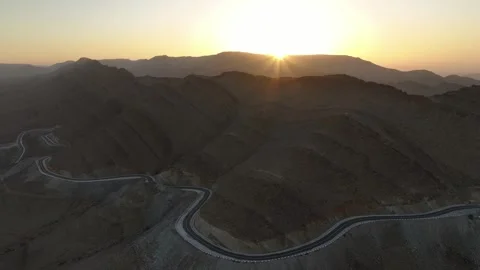Winding Mountain Road with Dramatic Sunburst over Desert Peaks Stock Footage 336618011