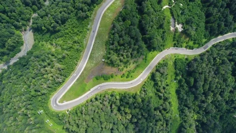 A winding mountain road in the forest, along which cars drive Stock Footage 165392276