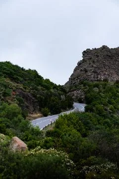 Winding mountain road leading into dramatic rock formations in tenerife Stock Photos