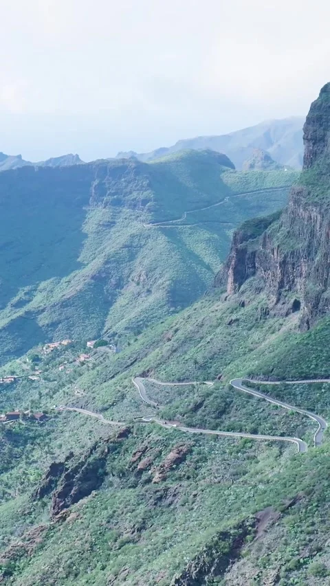 Winding mountain road snakes through green volcanic landscape Видео 329864701