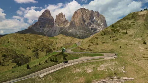Winding mountain road through green highlands and rugged peaks 動画素材 337078850