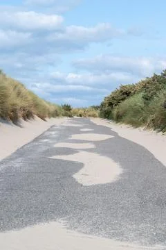 A Winding Path That Goes Through Sandy Dunes Beneath Overcast Cloudy Skies Above Stock Photos